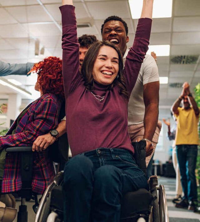 Portrait of a smiling woman with disability who won a office chair race | NDIS Core Supports Benefits - SIL Supported Independent Living